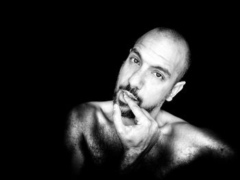 Portrait of shirtless man against black background