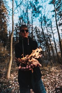 Man holding sunglasses in forest