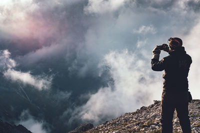 Man photographing at camera against sky