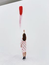 Rear view of woman standing against red wall