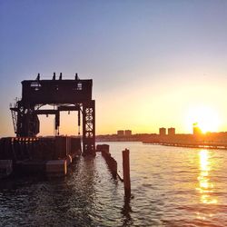 Pier in sea at sunset