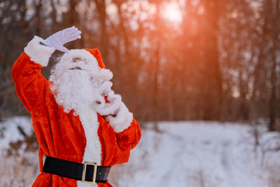 Santa clause shielding eyes outdoors during winter