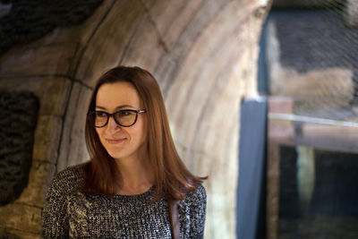 Smiling woman looking away while standing in corridor