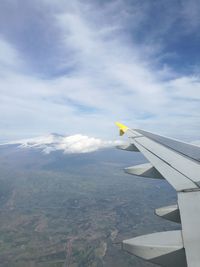 Cropped image of aircraft wing flying against sky