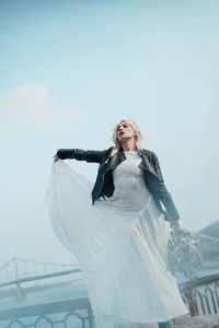 Low angle view of woman standing against sky