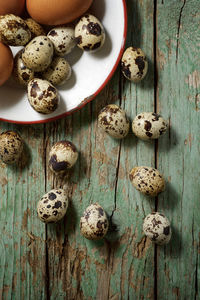 Quail and chicken eggs on a wooden table.