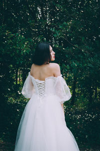 Woman looking away while standing on tree