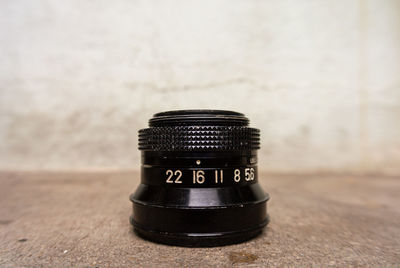Close-up of camera lens on floor against wall