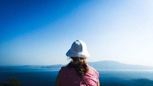 Rear view of woman standing by sea against clear sky