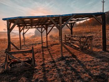 Metallic structure on field against sky during sunset