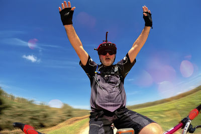 Rear view of woman with arms raised against sky