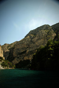 Scenic view of sea by mountains against sky