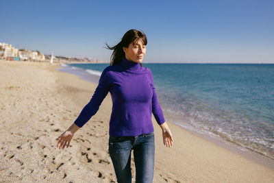 Beautiful mature woman relaxing breathing fresh air on a sunny winter day at the beach