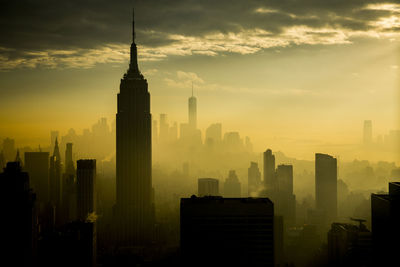 Modern buildings in city against sky during sunrise