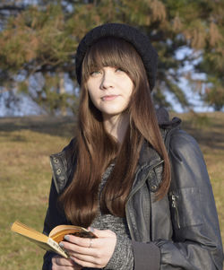 Close-up portrait of teenager with lip piercing holding book