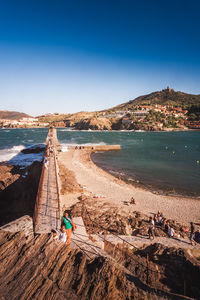 People on beach against clear blue sky