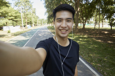 Portrait of smiling young man against trees