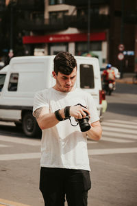 Man photographing while standing on road in city