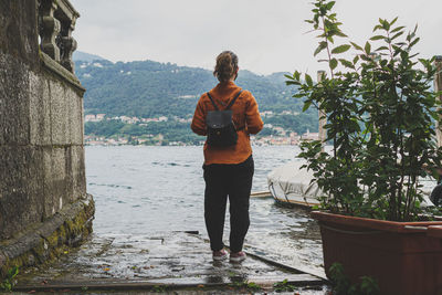 Rear view of woman standing by lake