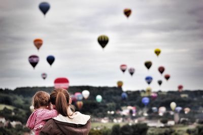 Rear view of mother and daughter looking at hot air balloons