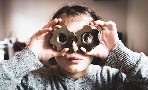 Close-up portrait of boy holding camera at home