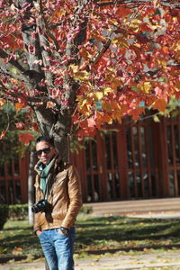 Portrait of man in sunglasses standing against tree