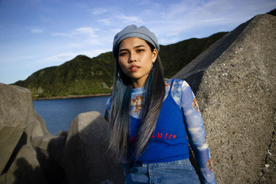 Portrait of young woman looking away against mountains