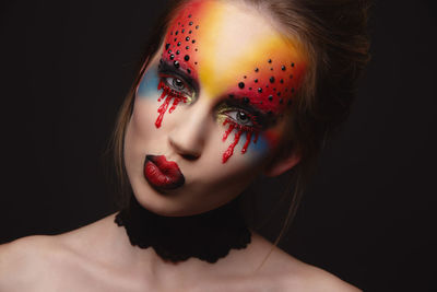 Close-up of young woman with face paint against black background