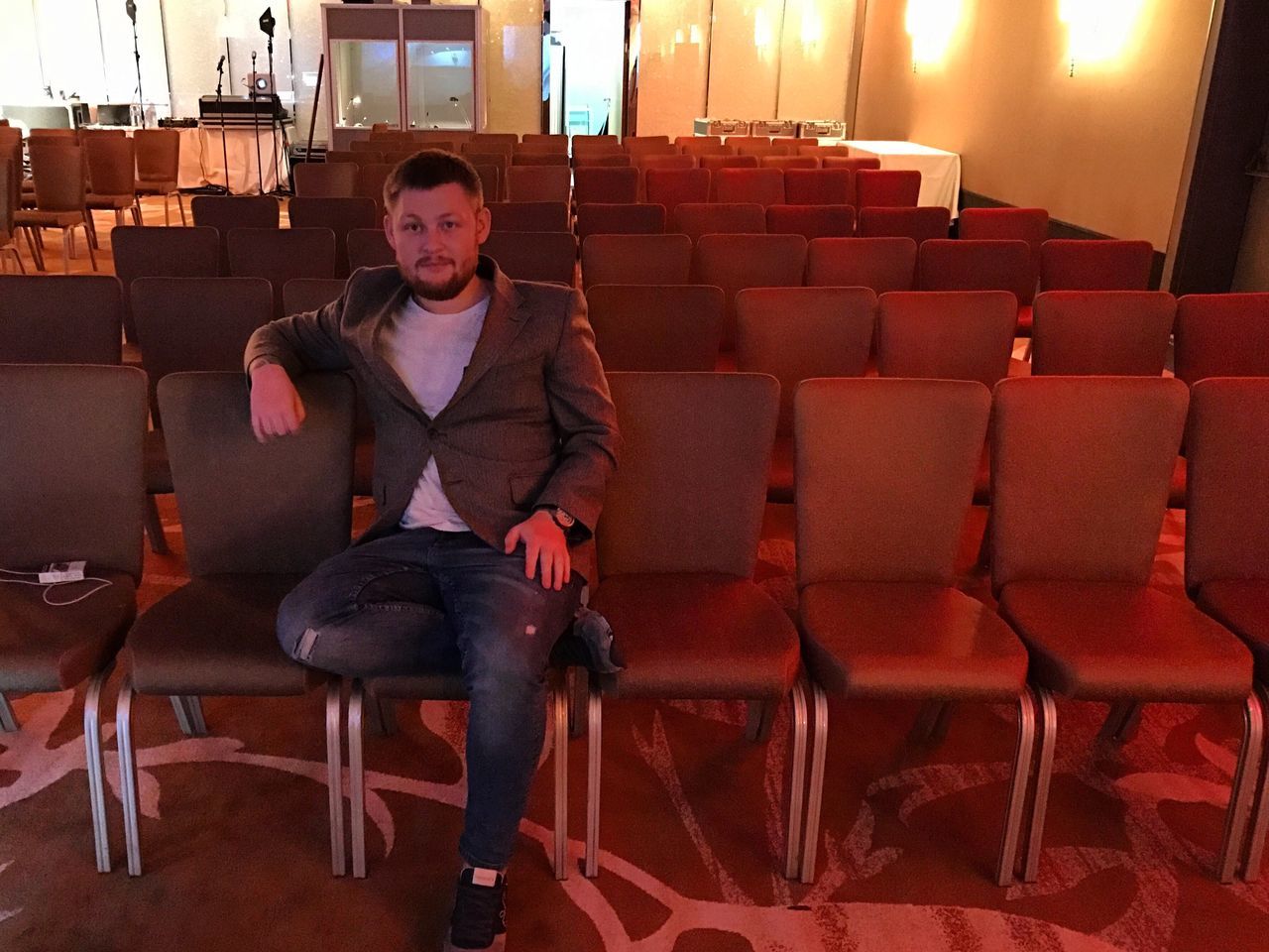 one man only, only men, men, adults only, chair, one young man only, one person, young men, beard, red, sitting, loneliness, young adult, adult, nightlife, people, portrait, leisure activity, city, seat, business finance and industry, indoors, auditorium, human body part