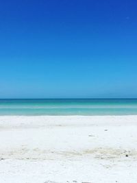 Scenic view of beach against clear blue sky