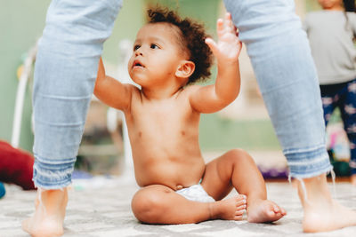 Low section of mother with son sitting on floor