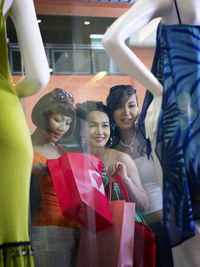 Friends looking at mannequin in shopping mall