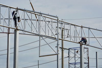 Low angle view of men working against sky