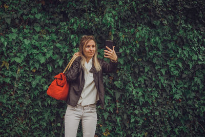 Young woman standing against plants