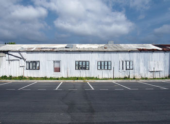 Empty road by buildings against sky