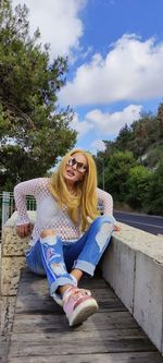 Portrait of smiling woman sitting against sky