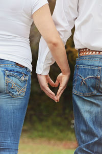 Cropped image of couple making heart shape with hands