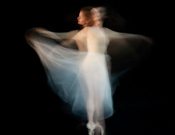 Midsection of woman dancing against black background