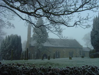 Church and cemetery against sky in foggy weather