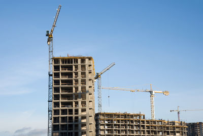 Low angle view of crane at construction site against sky