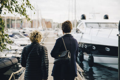 Rear view of senior women standing on pier amidst moored boats