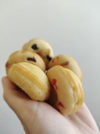 Close-up of hand holding apple against white background