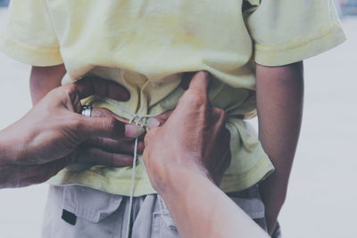 Cropped hand tying apron child back