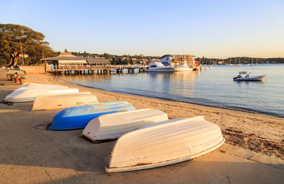 Boats moored in river at sunset
