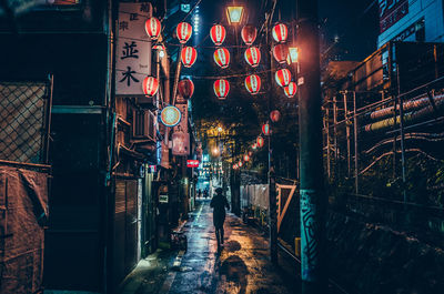 Illuminated lanterns hanging over street at night