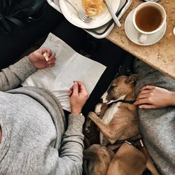 High angle view of woman holding coffee while sitting on floor