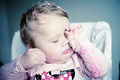 Close-up of baby girl with cake on face at home