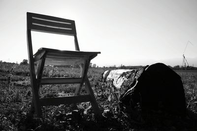 Abandoned chair on field against clear sky