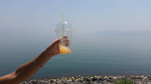 Cropped hand holding slush against lake tiberius during foggy weather