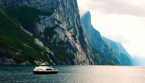 Sailboat on sea by mountains against sky